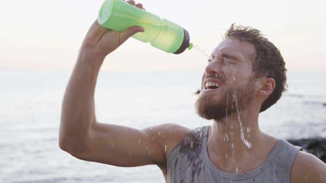 athlete-drinking-water-from-bottle-splashing-water-in-face-cooling-down-aft-1528839906421.jpg
