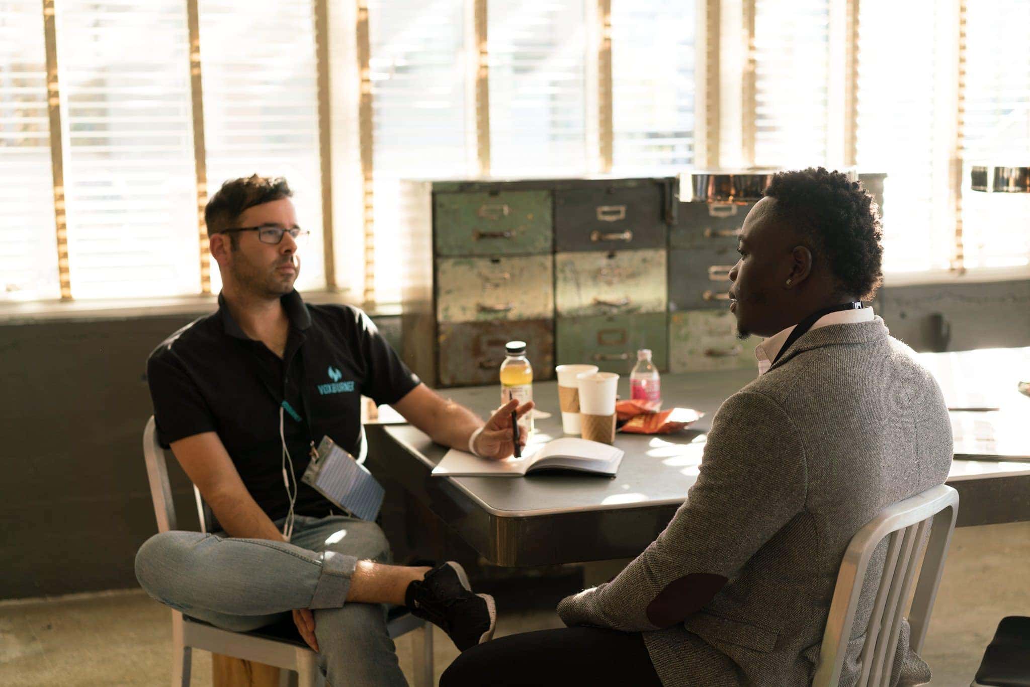 Canva - Man Wearing Black Polo Shirt and Gray Pants Sitting on White Chair