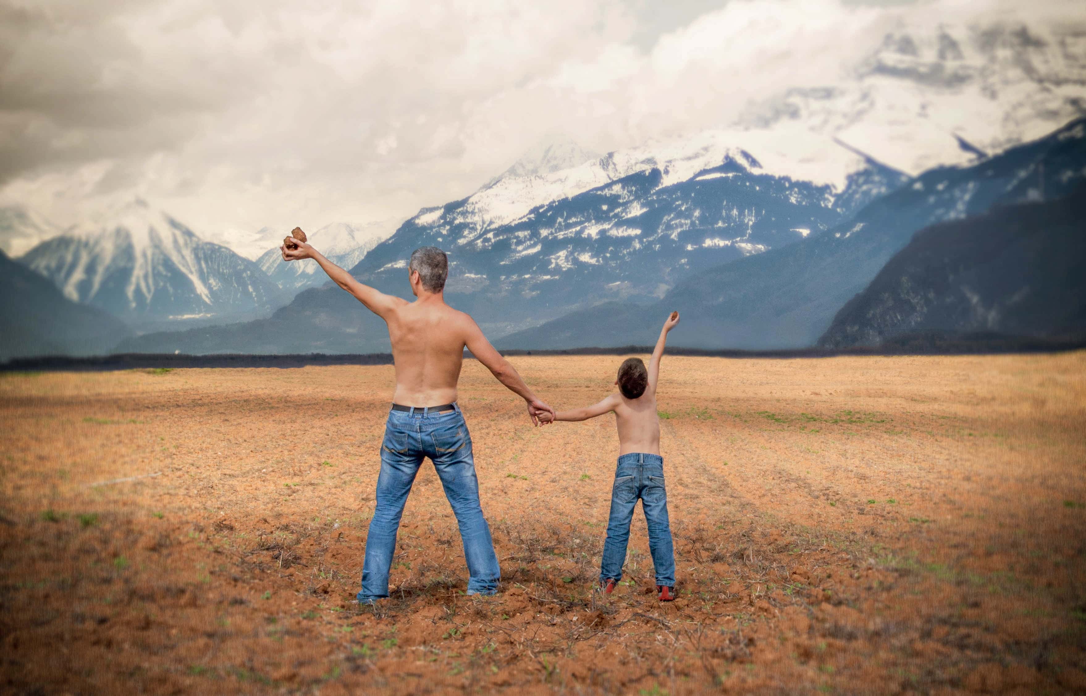 Canva - Man and a Boy in Blue Denim Jeans Standing in Brown Open Space Near White and Gray Snowy Mountains during Daytime