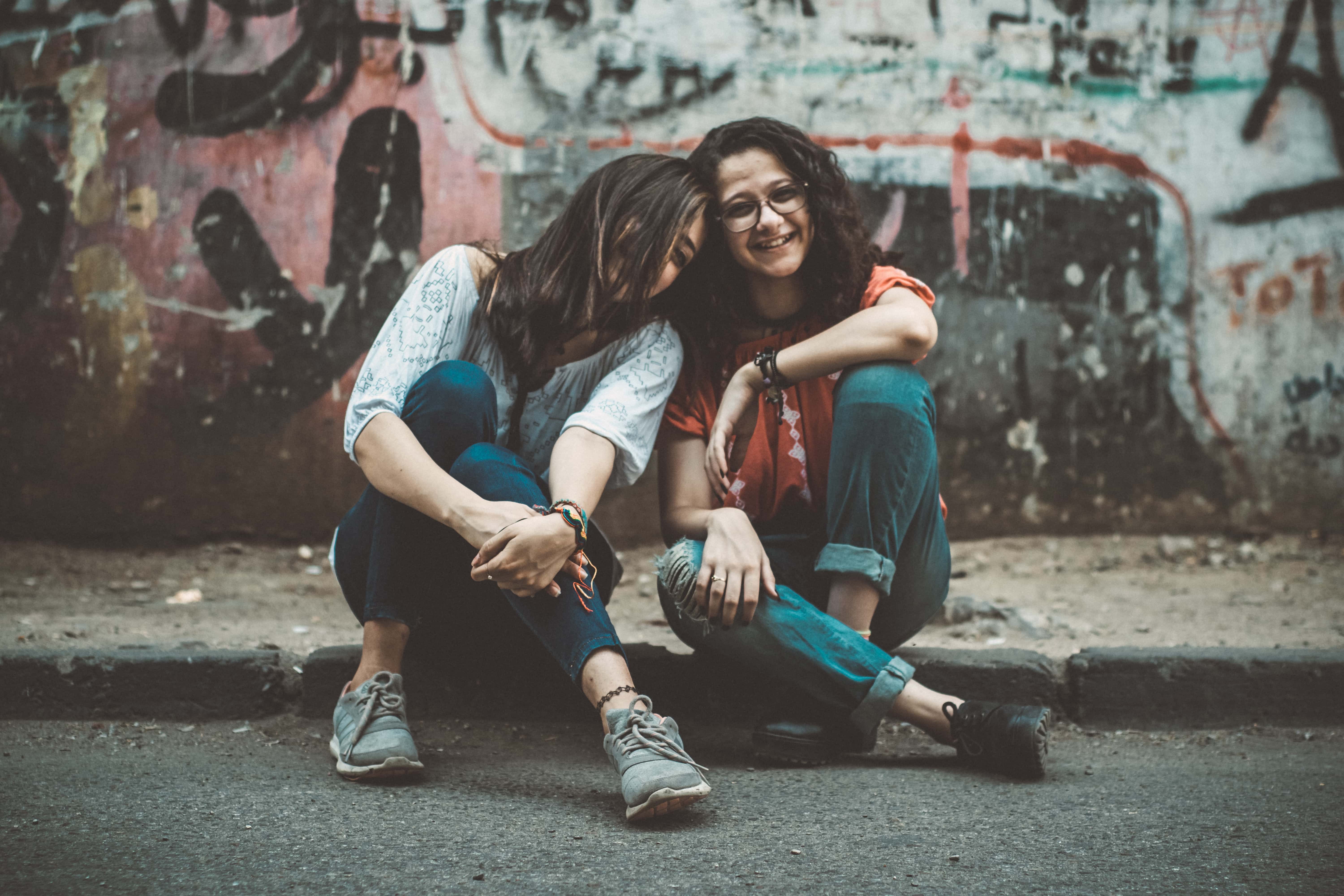 Canva - Two Women Sitting on Pavement Near Painted Wall