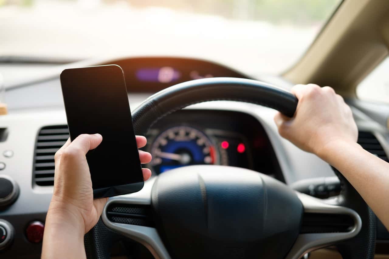 person-holding-black-smartphone-and-vehicle-steering-wheel-1028742