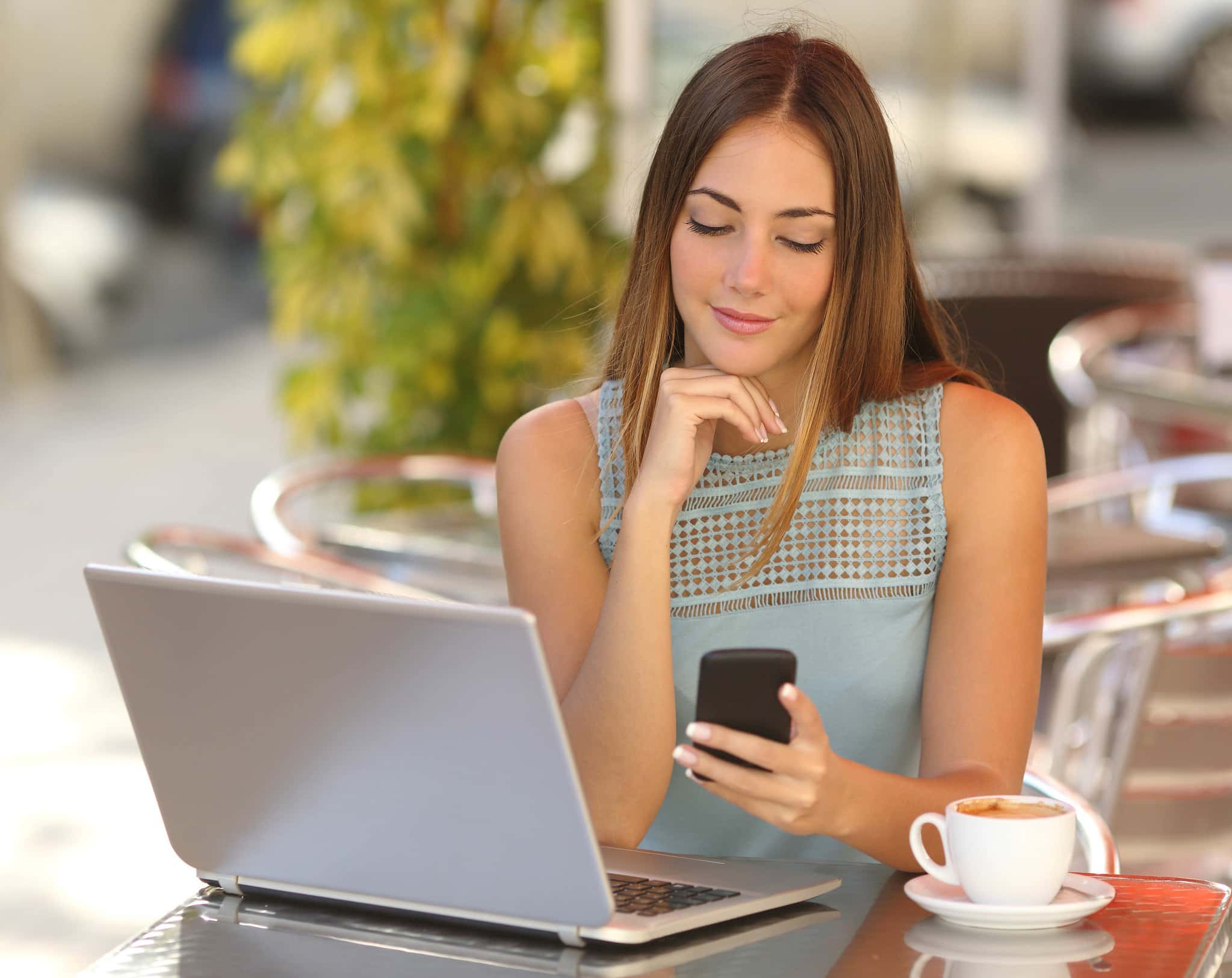 Self employed woman working with her phone and laptop in a resta