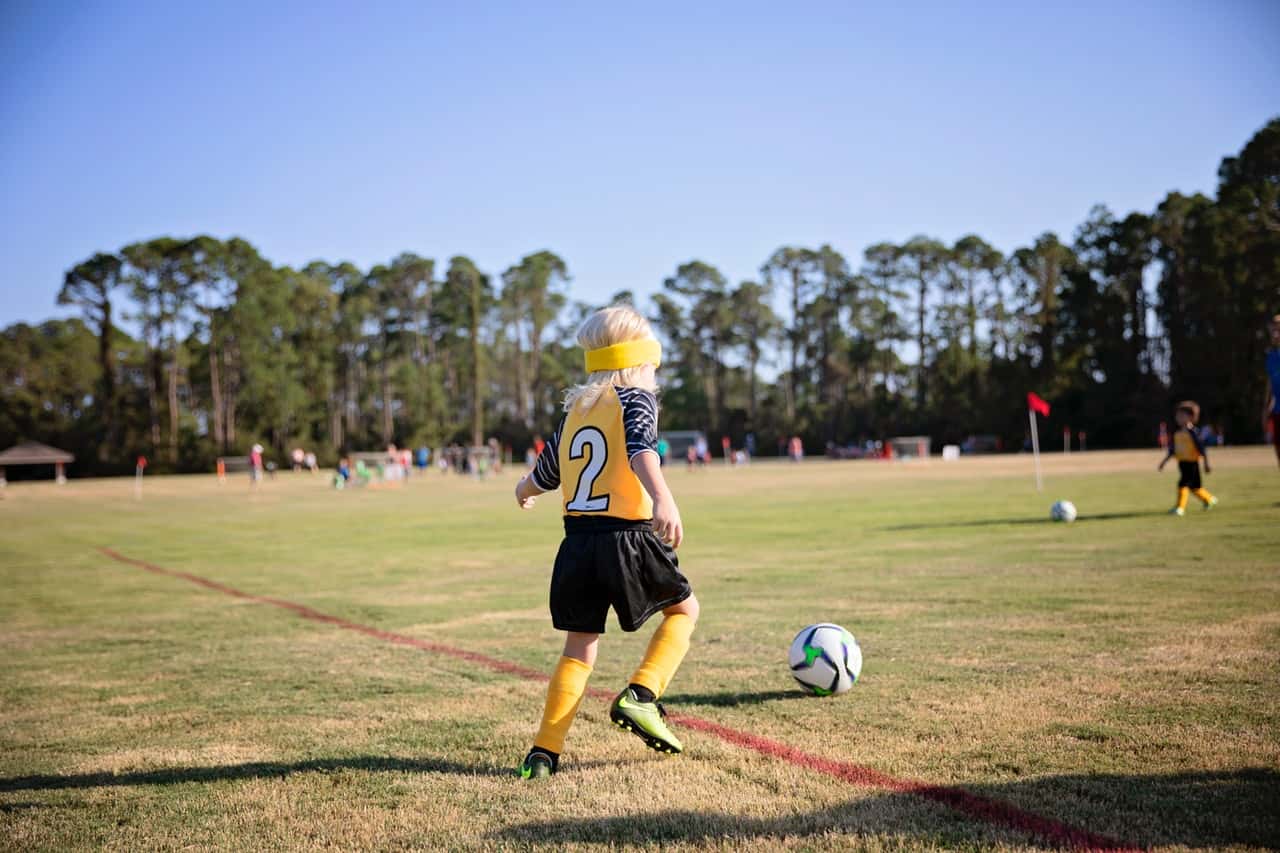 boy-wearing-yellow-and-white-jersey-playing-soccer-field-3006119