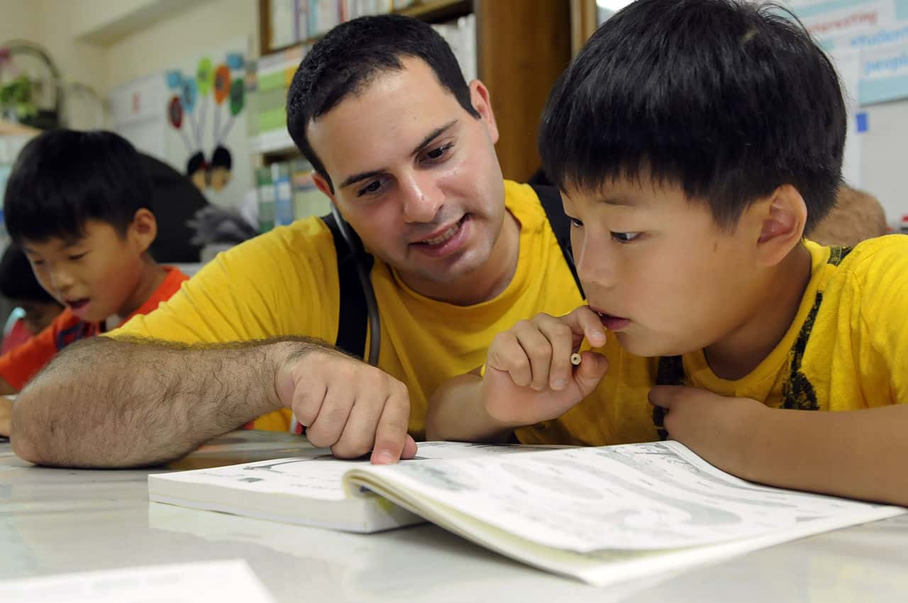 US_Navy_100819-N-7478G-463_Logistics_Specialist_2nd_Class_Riad_Tah_helps_a_child_with_his_English_lesson