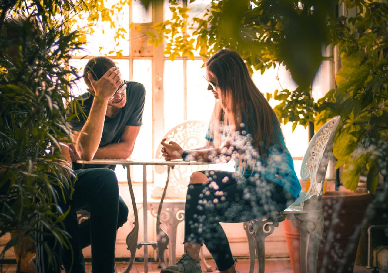 man-and-woman-sitting-on-chairs-beside-a-table-2934546