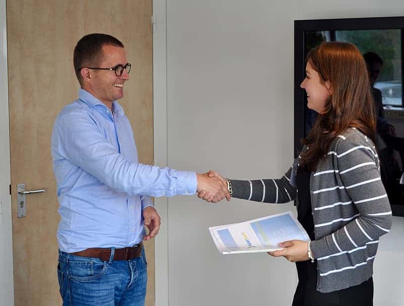 man-in-blue-dress-shirt-shaking-hands-with-woman-in-white-and-grey-striped-zip-up-jacket