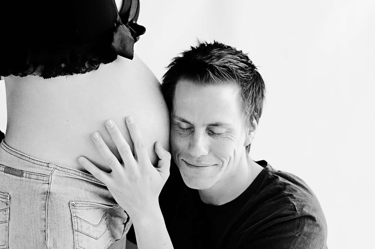 man-wearing-black-listening-on-pregnant-woman-s-stomach-35200