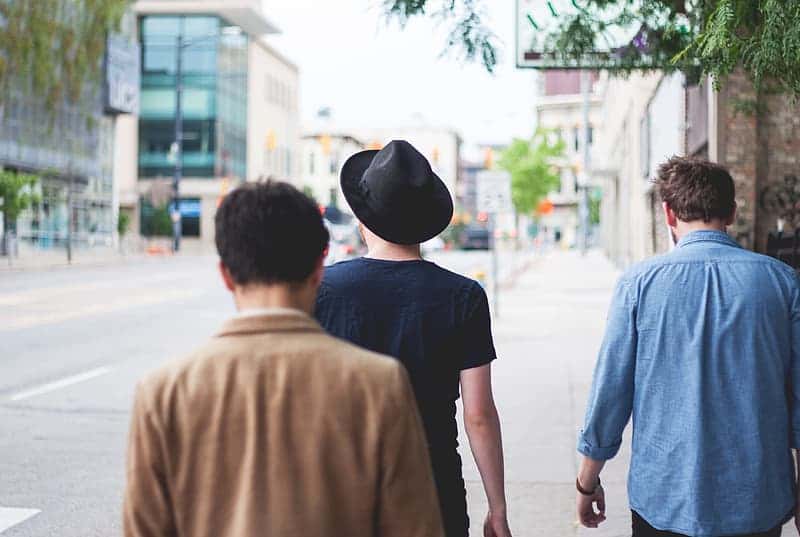 three-men-walking-on-road-under-green-tree-at-daytime