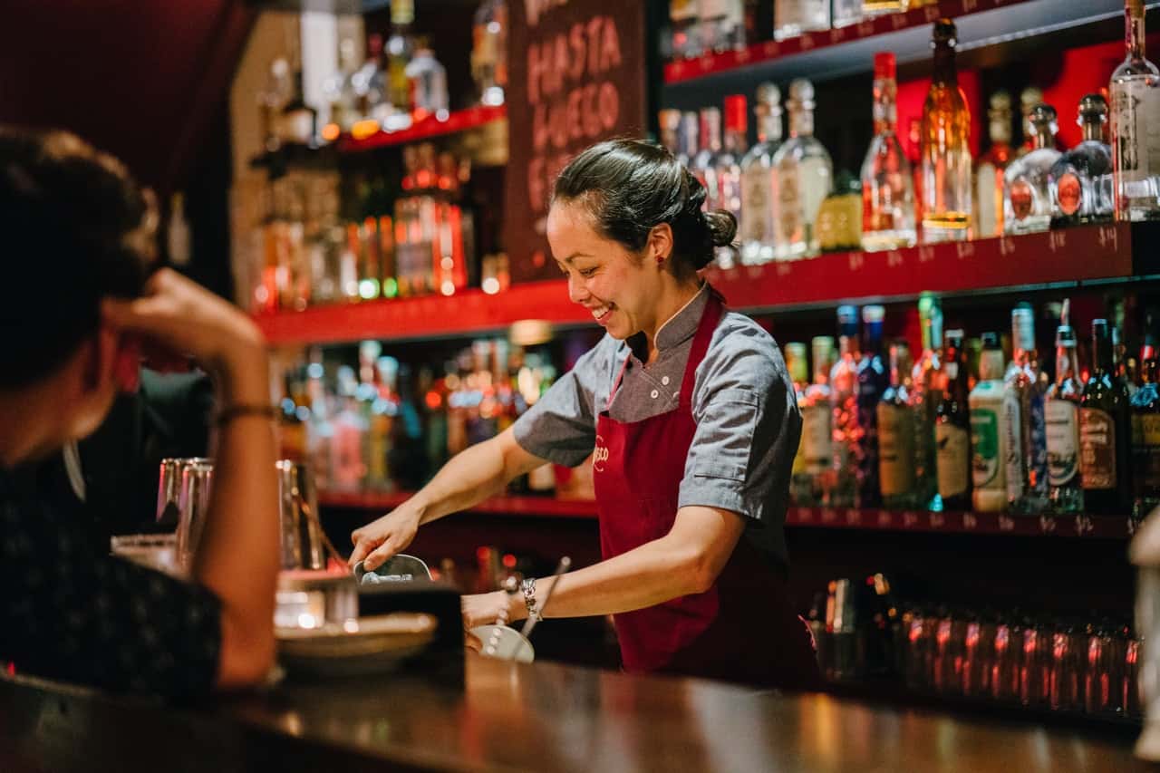 woman-bartender-smiling-while-mixing-liqueurs-1301547