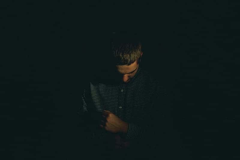 man-looking-down-while-holding-his-clothes-sleeves