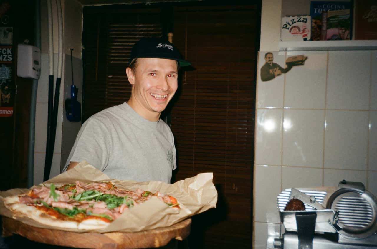 man-standing-and-smiling-while-holding-pizza-2291445