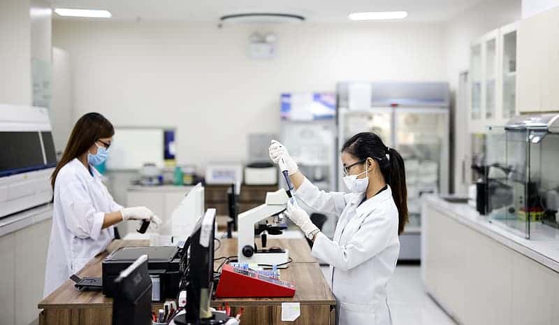 woman-in-white-lab-coat-standing-in-front-of-desk
