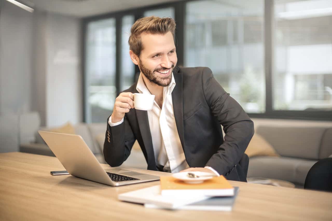 man-holding-white-teacup-in-front-of-gray-laptop-842567