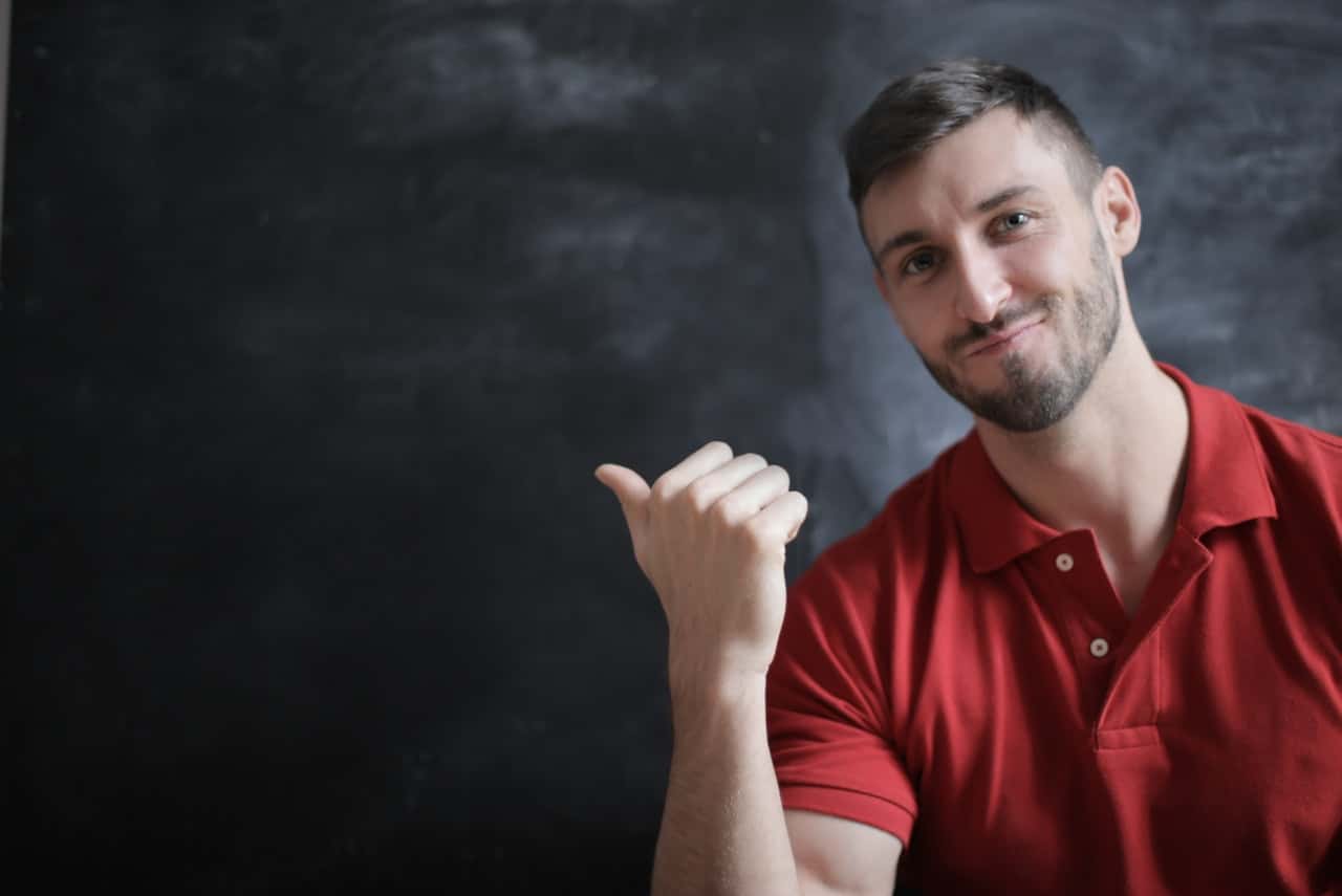 man-in-red-polo-shirt-sitting-beside-chalkboard-3779436