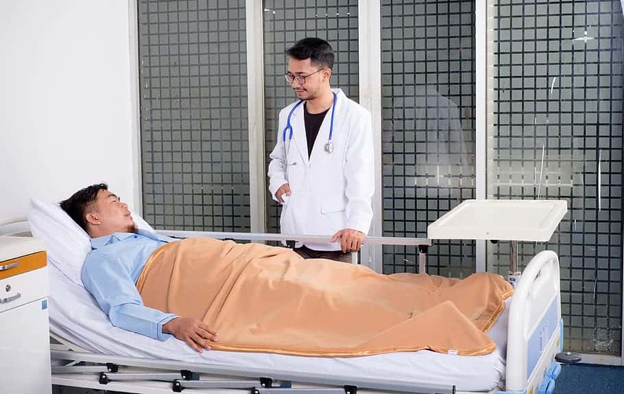 man-lying-on-bed-talking-to-doctor