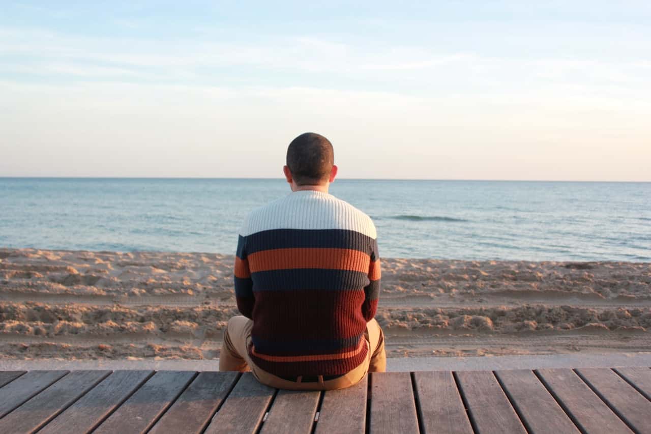 man-sitting-on-wooden-panel-facing-in-the-ocean-207920