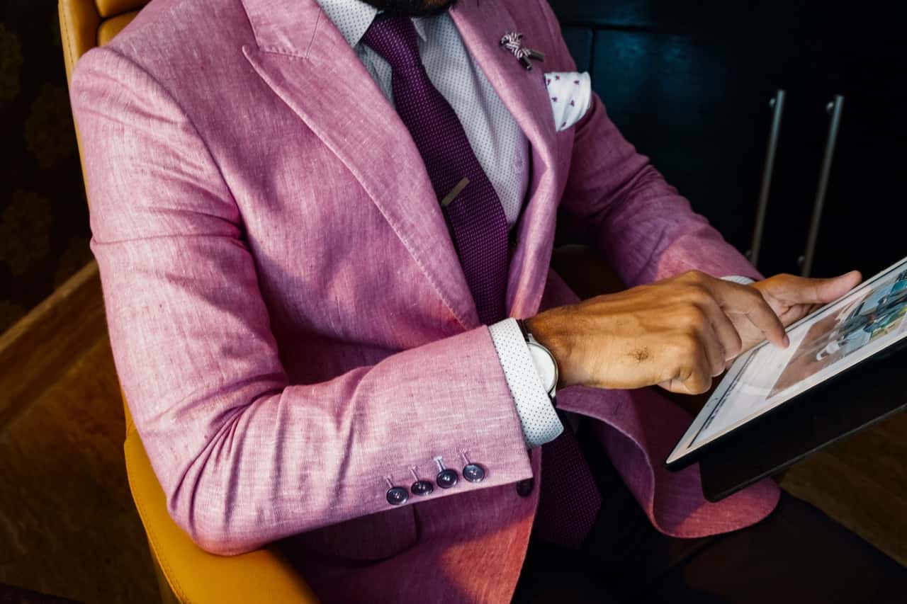 man-wearing-pink-suit-jacket-holding-using-tablet-computer-1303862