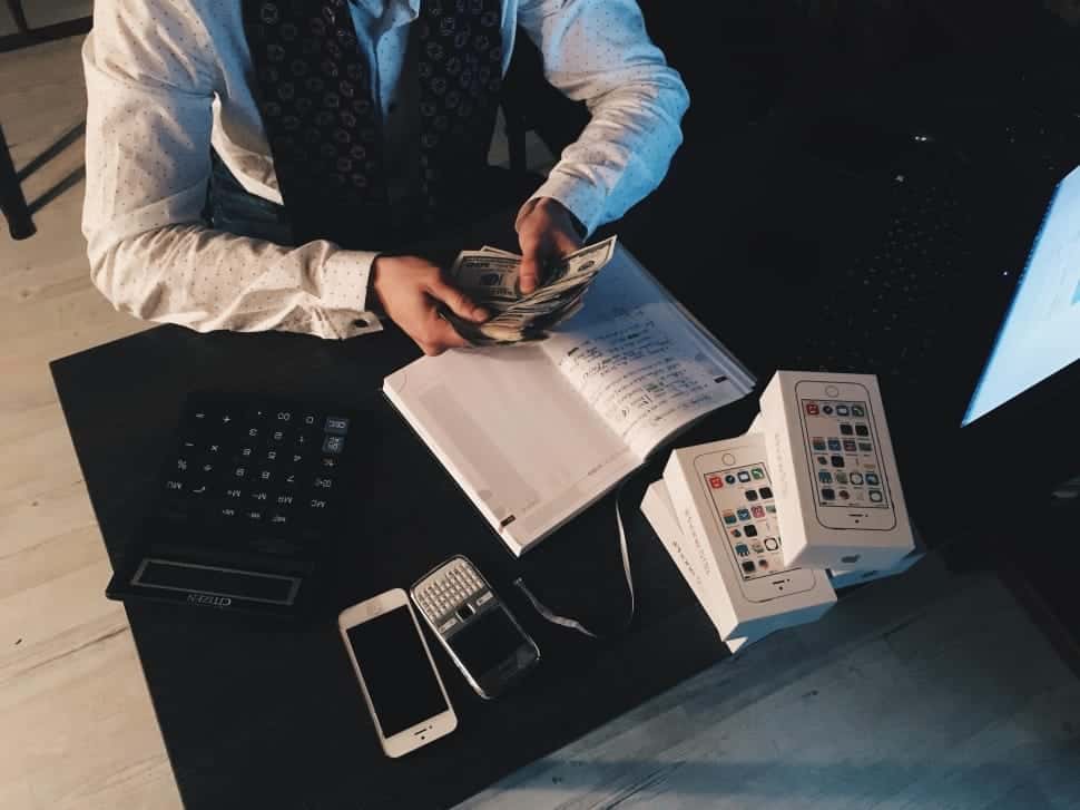 person-counting-money-with-smartphones-in-front-on-desk-wallpaper-preview