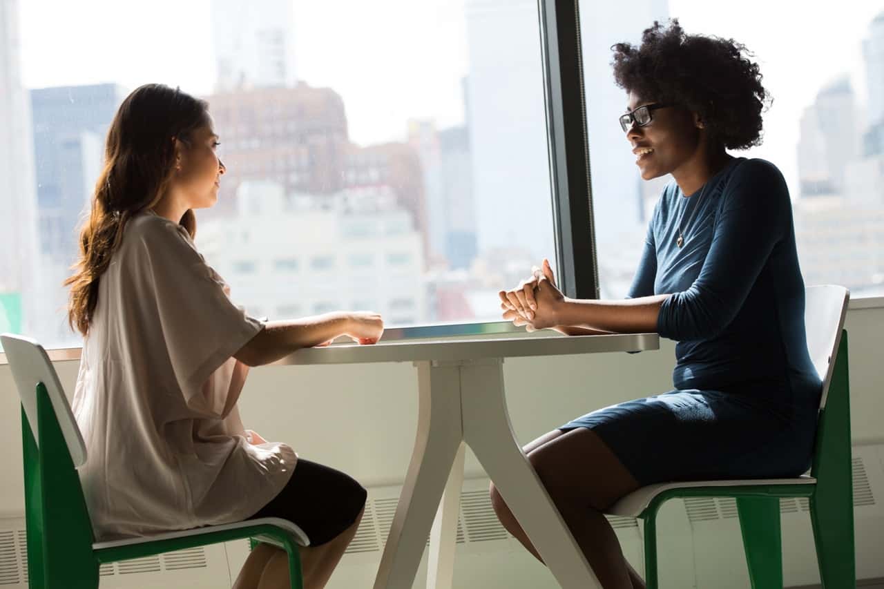 two-women-sitting-on-chairs-beside-window-1181719
