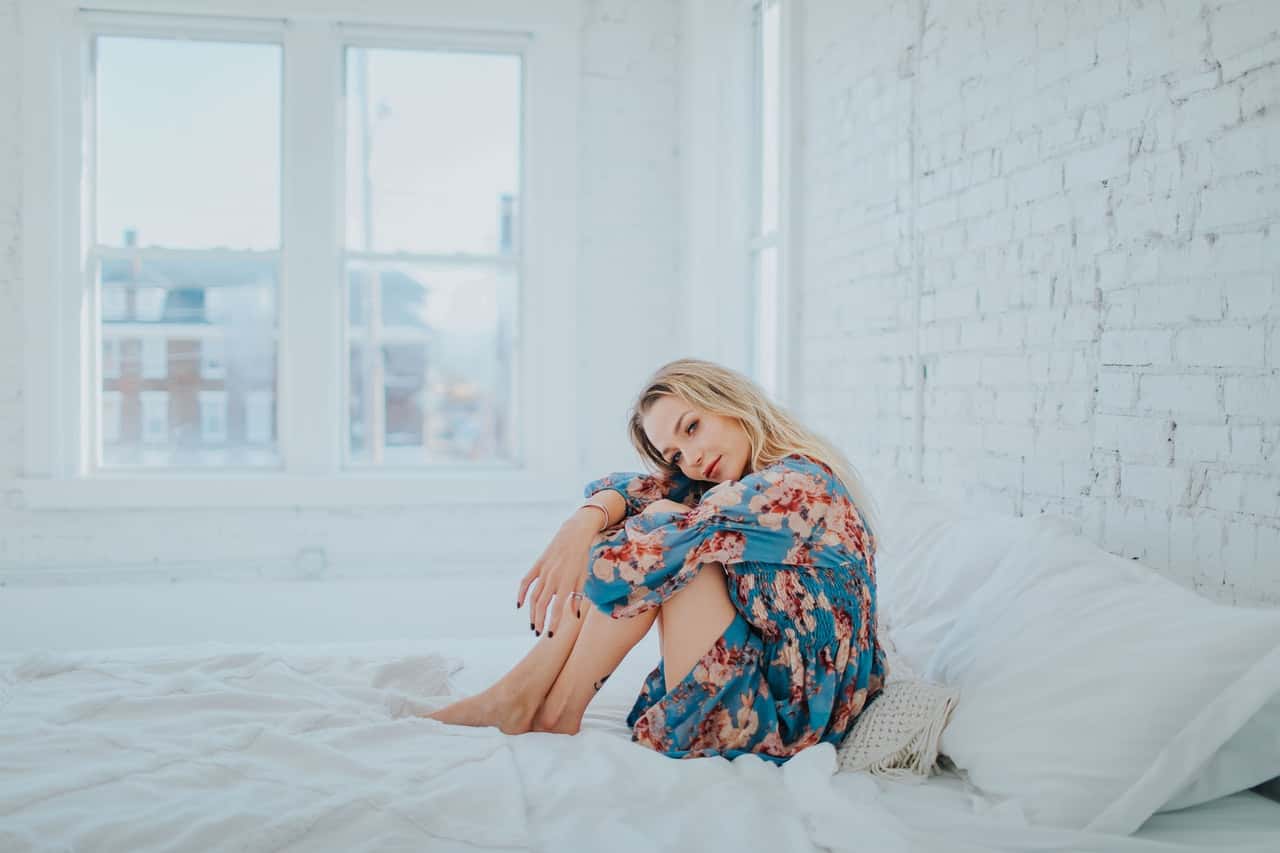 woman-wearing-floral-dress-while-sitting-on-bed-3586911