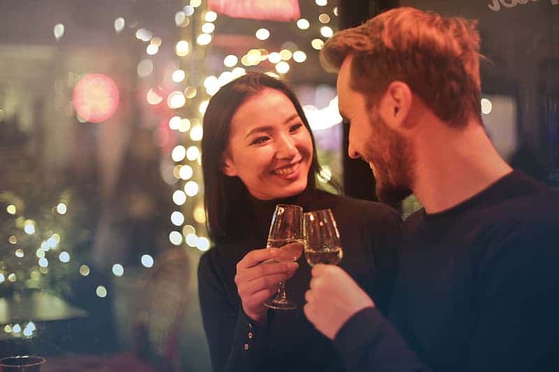 young-couple-clanging-wine-glasses-in-a-bar-during-a-date-night-out