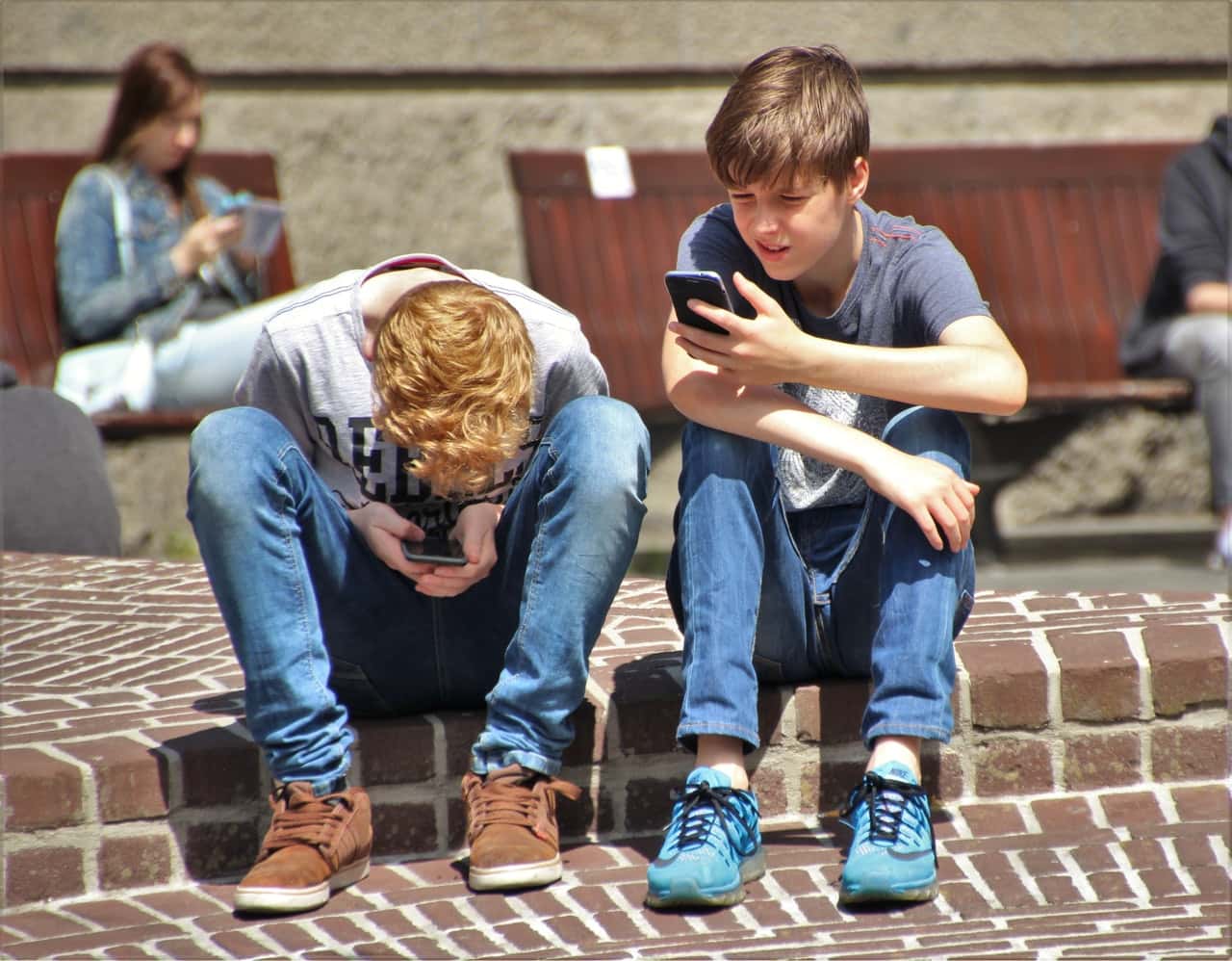 2-boy-sitting-on-brown-floor-while-using-their-smartphone-159395