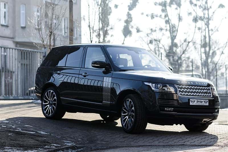 black-land-rover-range-rover-suv-parked-on-pavement-near-fence-and-buildin