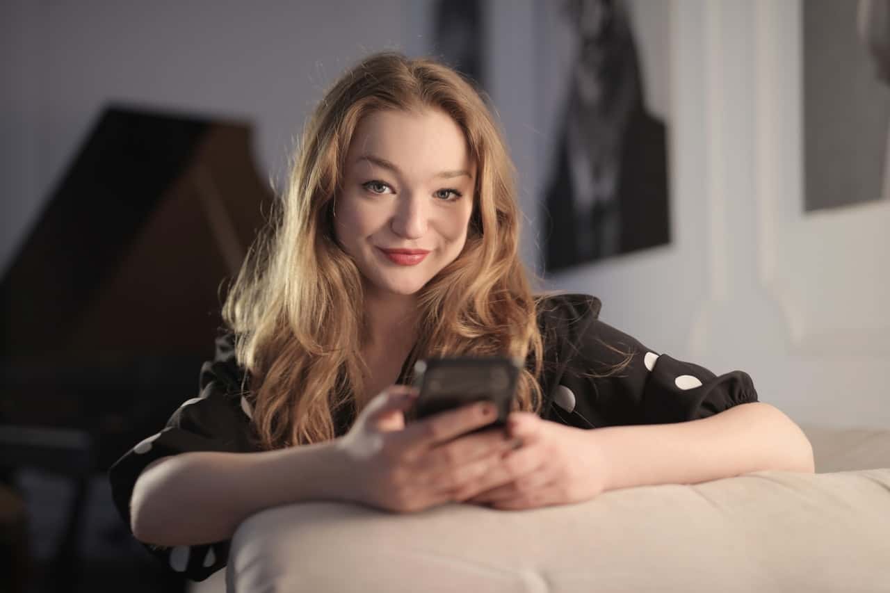 charming-woman-messaging-on-smartphone-in-living-room-3831850