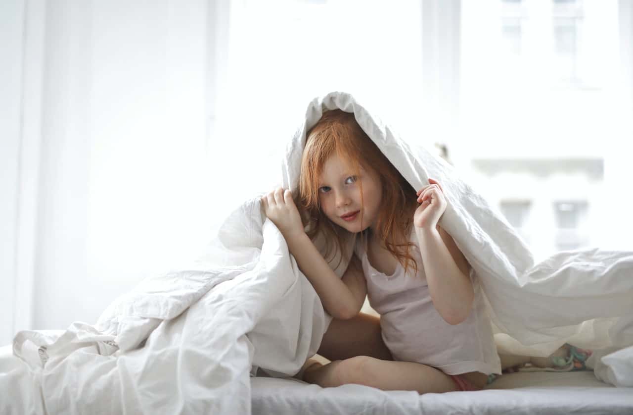 child-covering-her-body-in-a-white-comforter-3755712