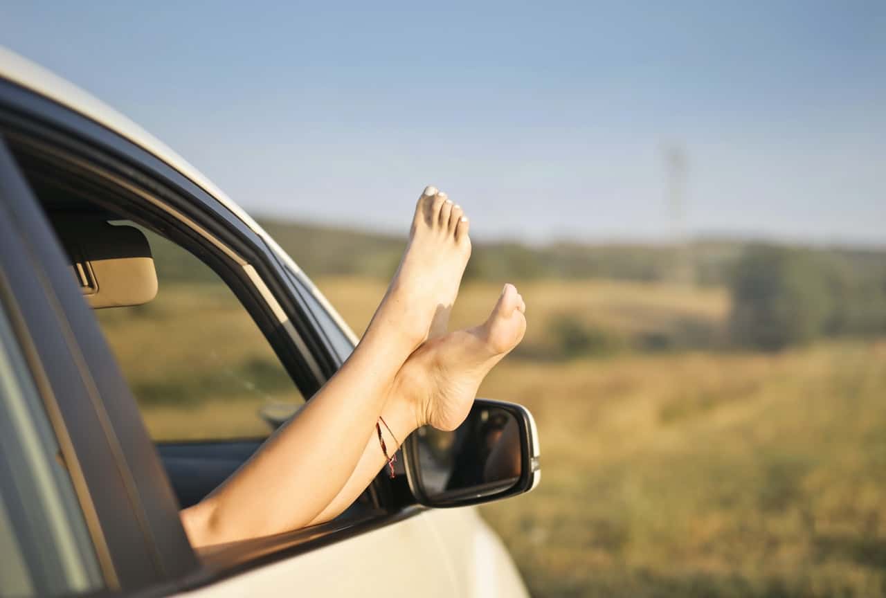 crop-carefree-woman-with-legs-sticking-out-of-car-window-3756167