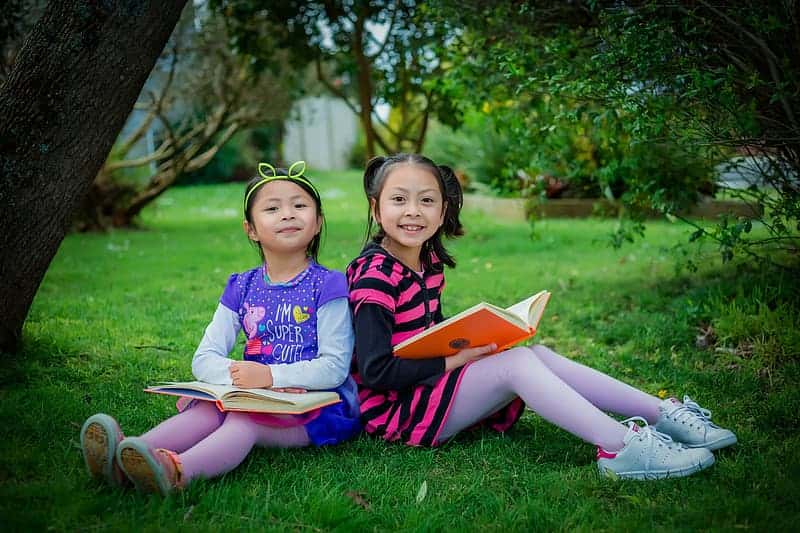 girl-in-blue-and-white-crew-neck-t-shirt-sitting-on-green-grass-field-reading-book