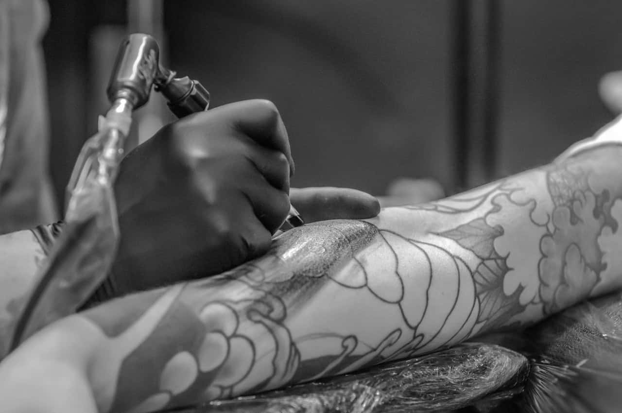 grayscale-photo-of-person-applying-tattoo-955938