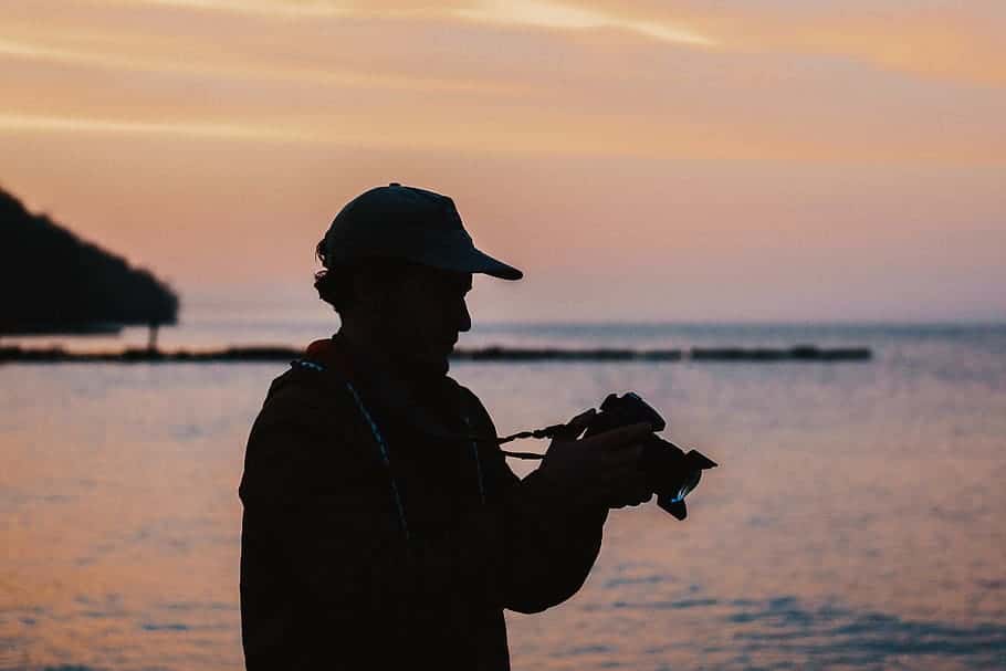 man-doing-photography-using-dslr-camera-near-body-of-water