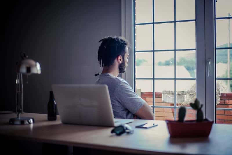 man-wearing-grey-shirt-sitting-on-chair-front-of-window