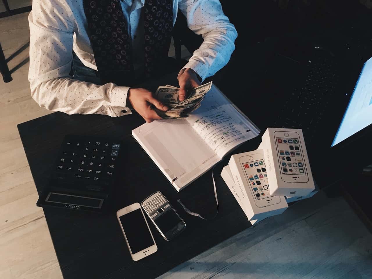 person-counting-money-with-smartphones-in-front-on-desk-210990