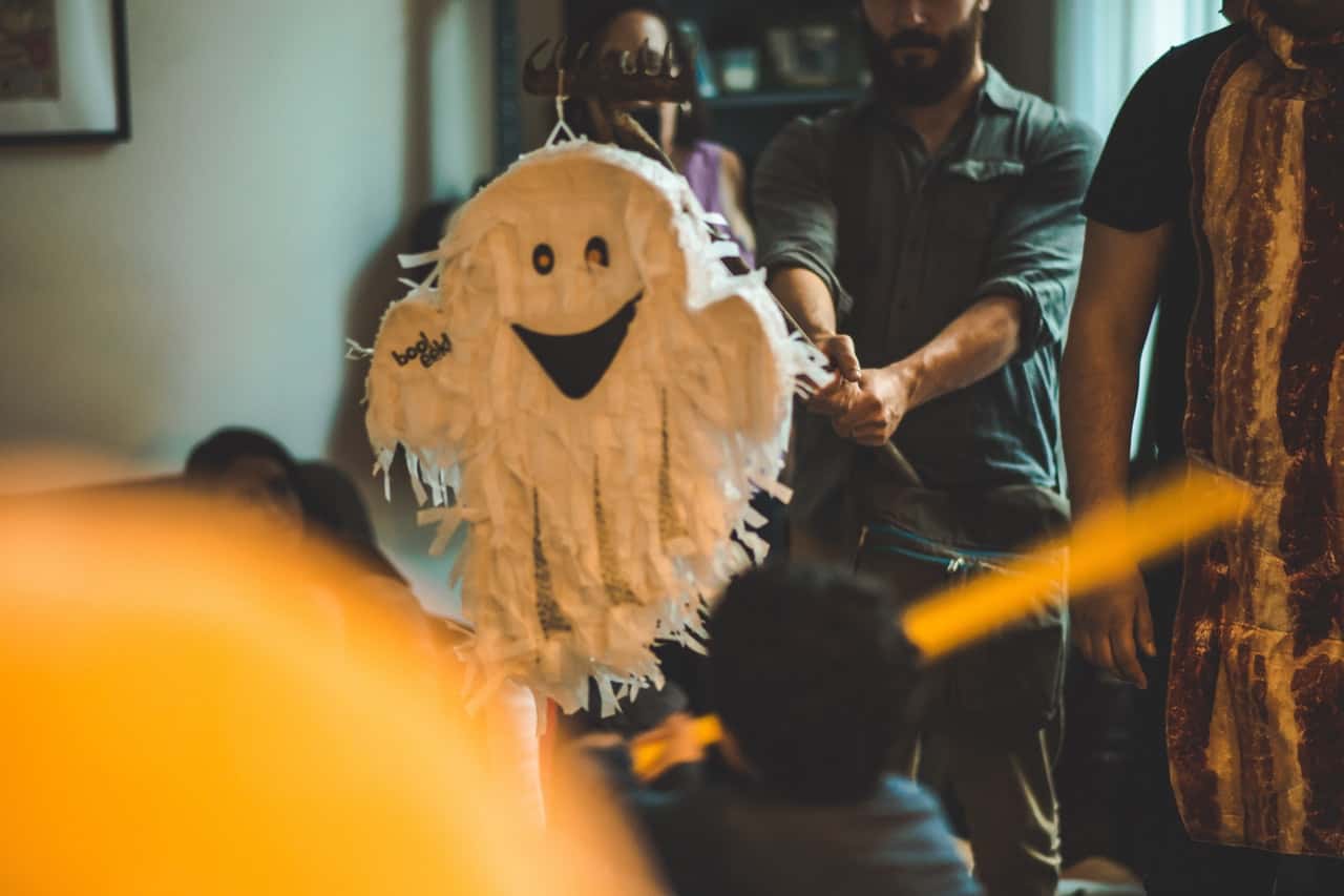 person-holding-stick-in-front-of-white-ghost-pinata-1557769