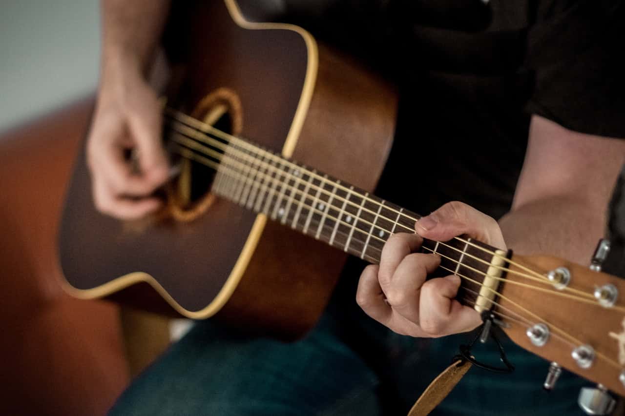 person-playing-brown-guitar-1407322