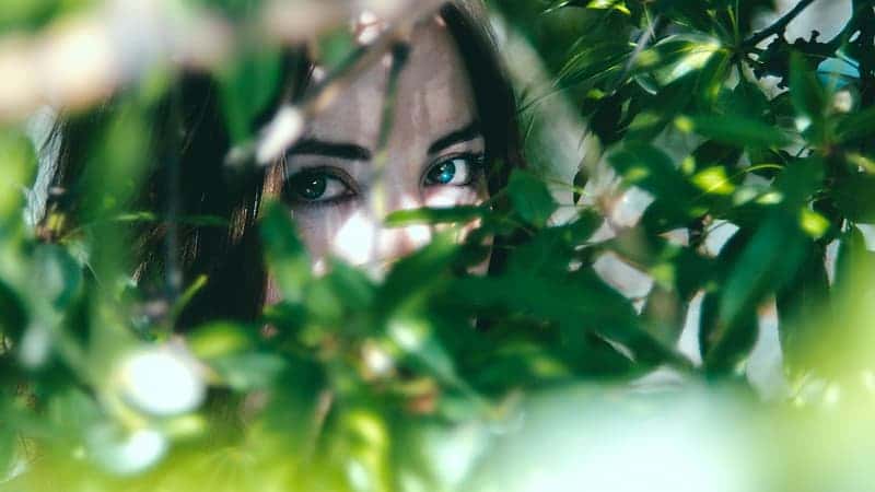 woman-hiding-on-green-leaf-plant