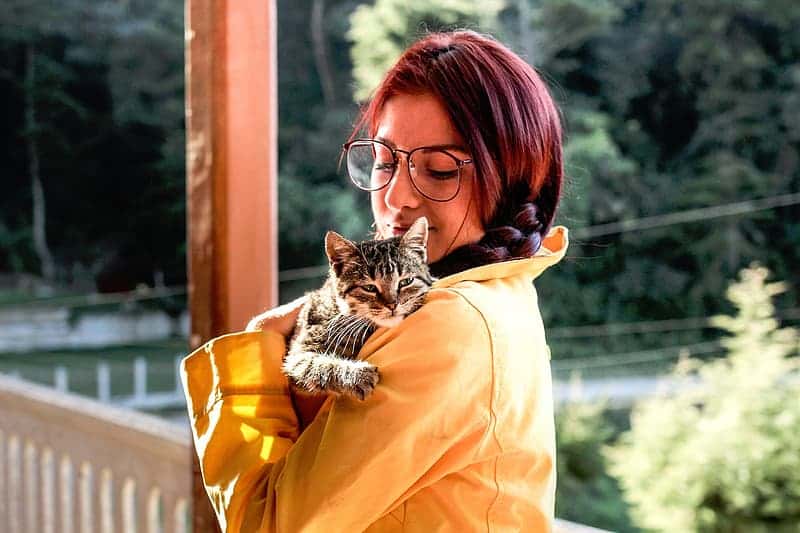 woman-holding-black-cat-near-balustrade