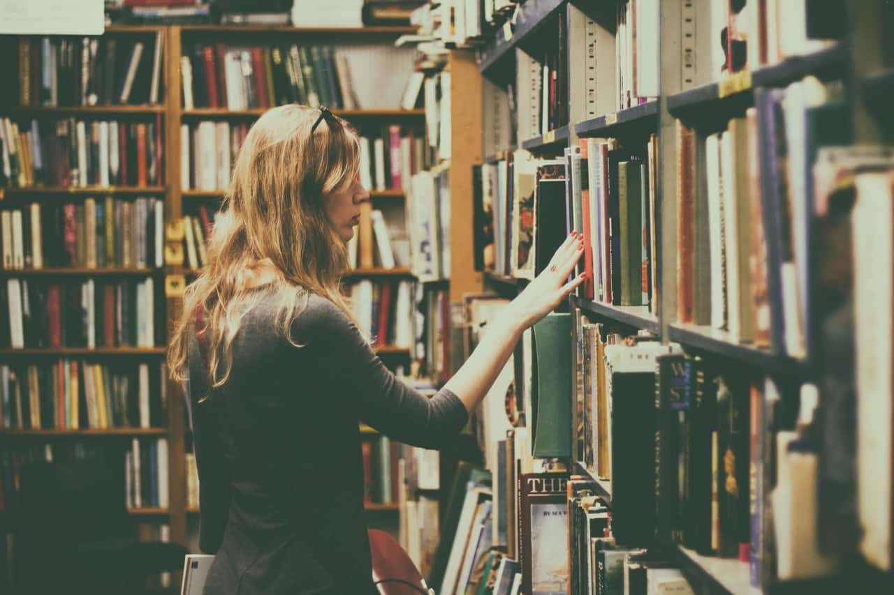 woman-in-black-long-sleeved-looking-for-books-in-library-926680