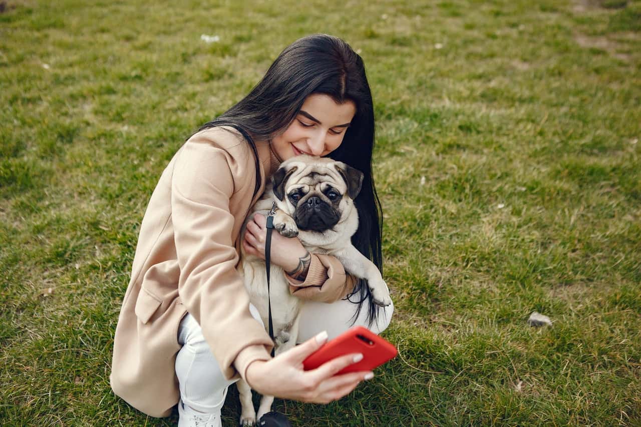 woman-in-brown-coat-holding-her-dog-while-taking-selfie-4148827
