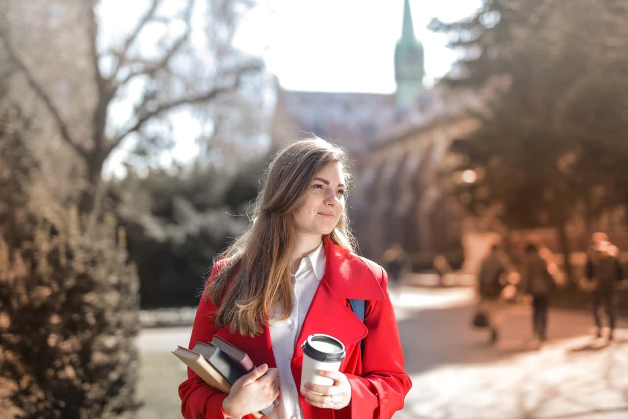 woman-in-red-coat-holding-notebooks-and-coffee-cup-3755760