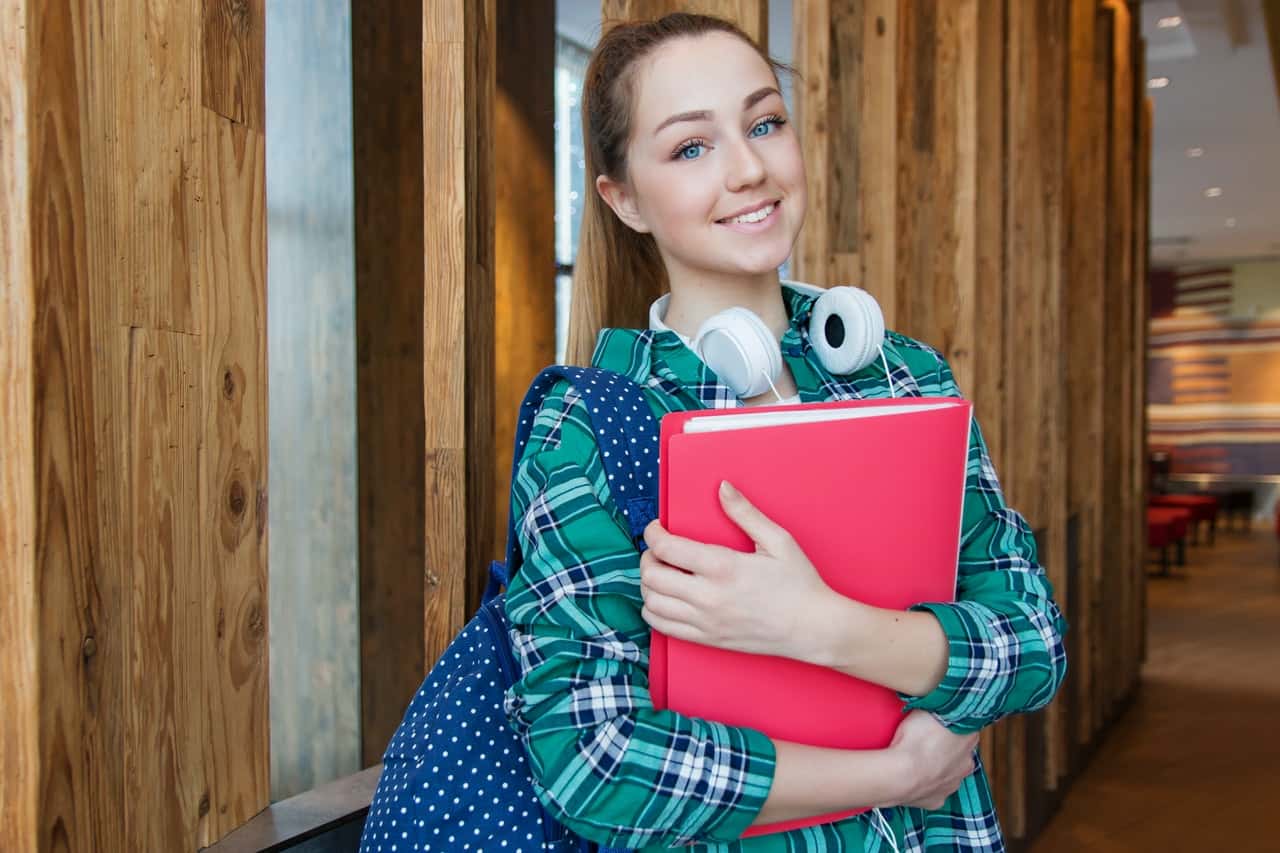 woman-standing-in-hallway-while-holding-book-1462630