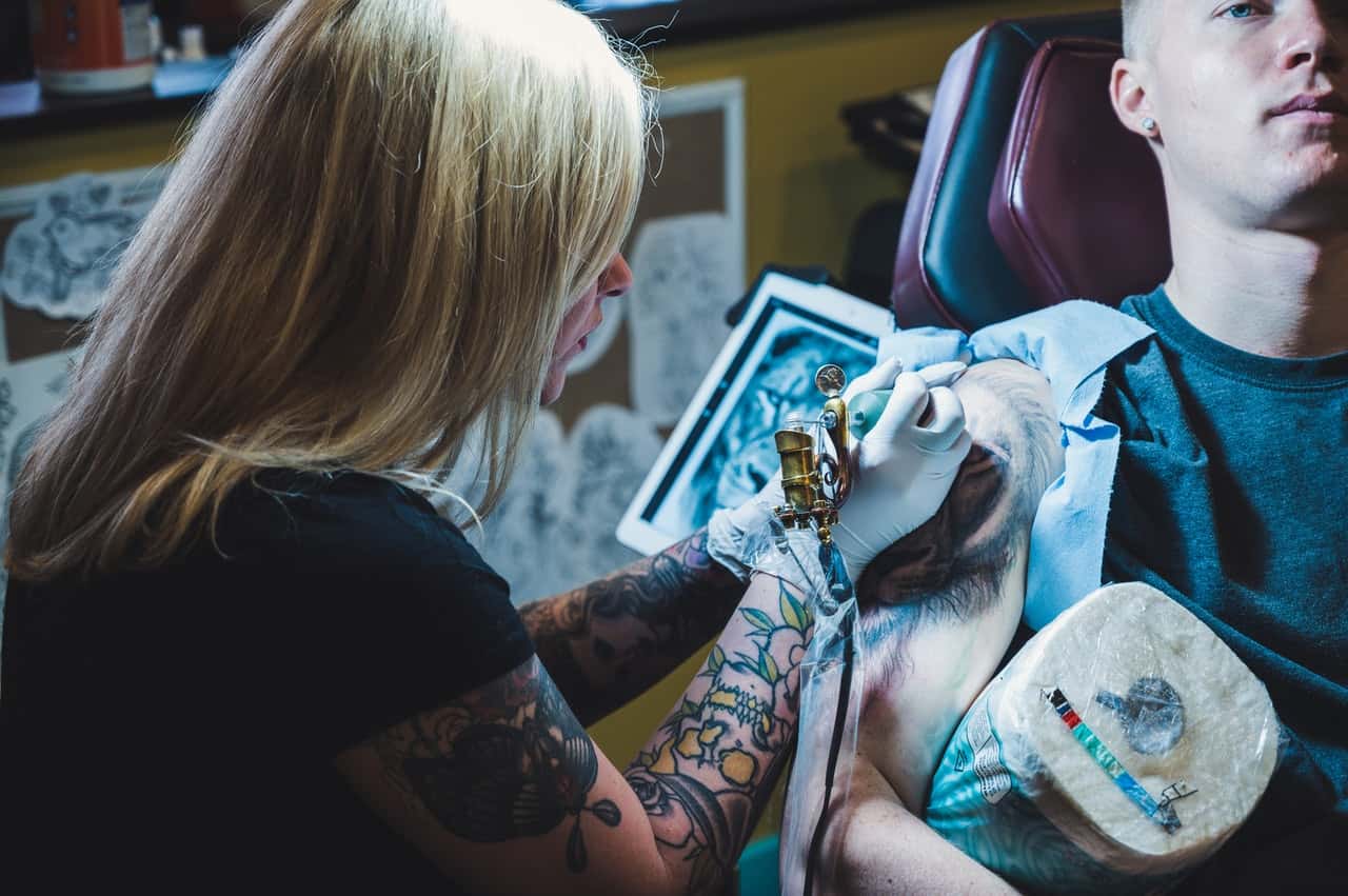 woman-tattooing-man-on-his-right-arm-2177016