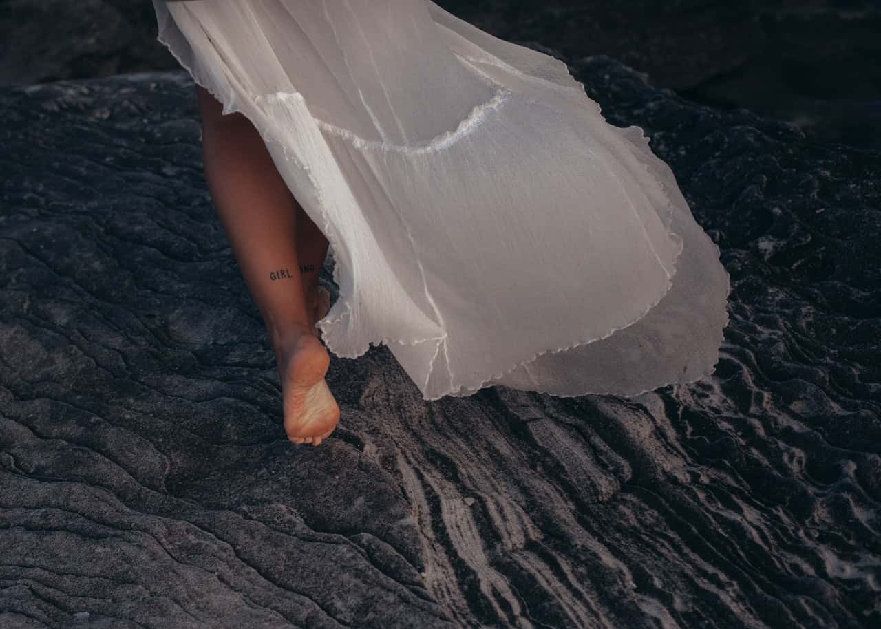 woman-wearing-white-dress-walking-on-sand-2029253