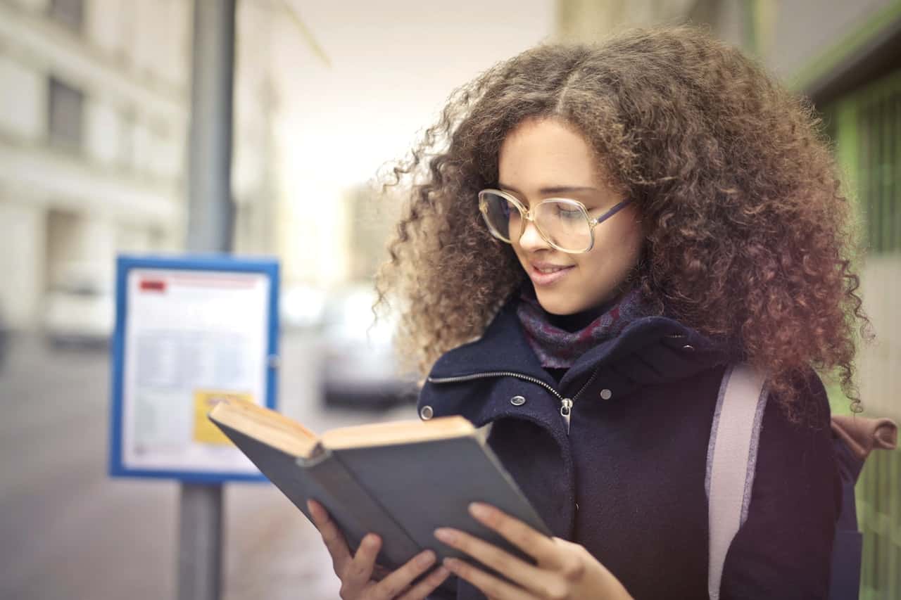 woman-with-curly-hair-wearing-eyeglasses-reading-book-3772508