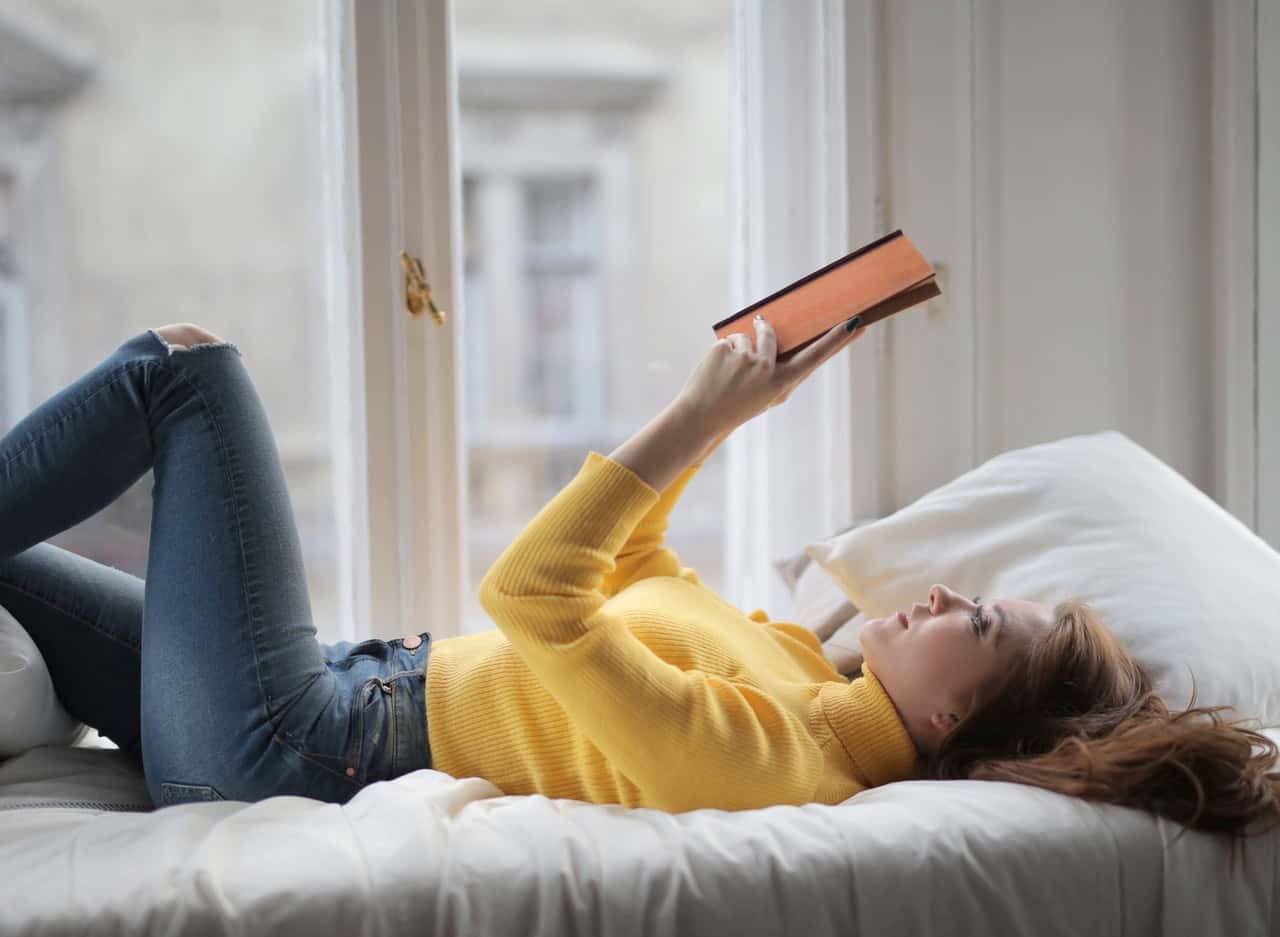 young-peaceful-woman-reading-book-on-bed-3884301