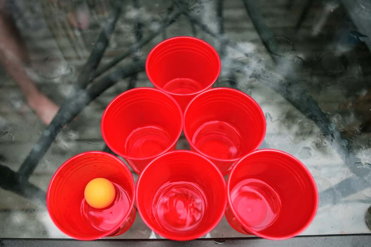 close-up-photo-of-red-beer-pong-cups-and-ball-on-glass-table-544991