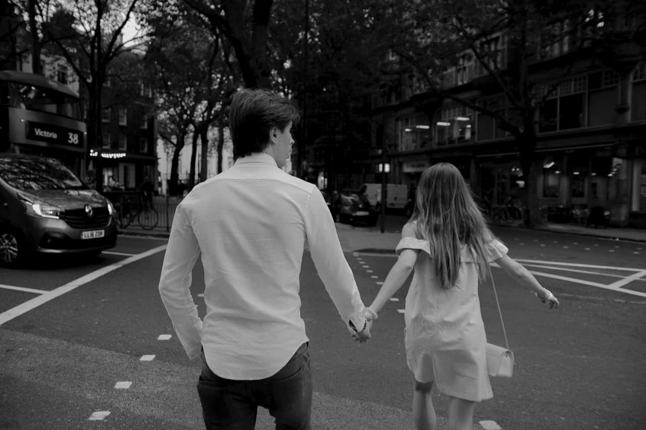 grayscale-photography-of-man-and-woman-holding-hands-on-road-2029317