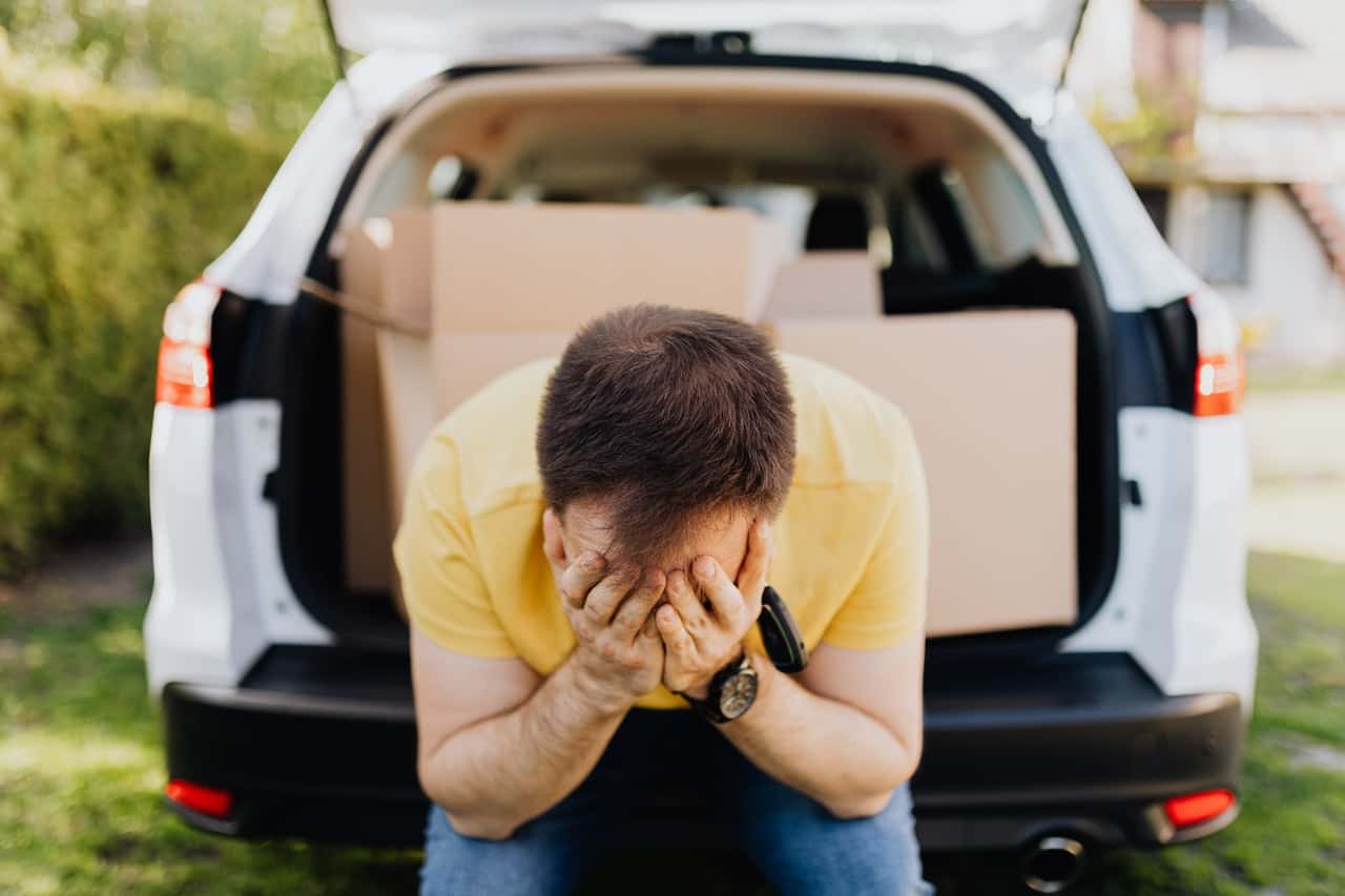 man-covering-face-with-hands-near-car-trunk-4506212